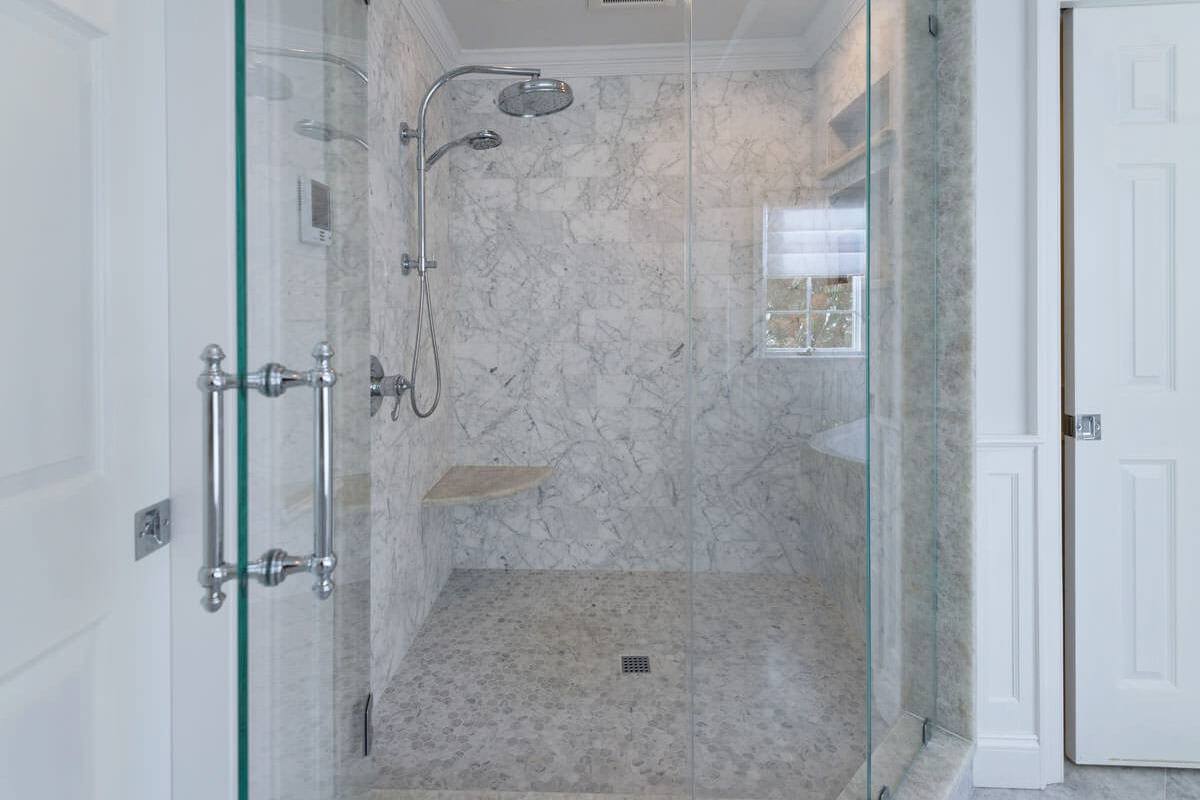 Glass shower enclosure lined with Carrara marble