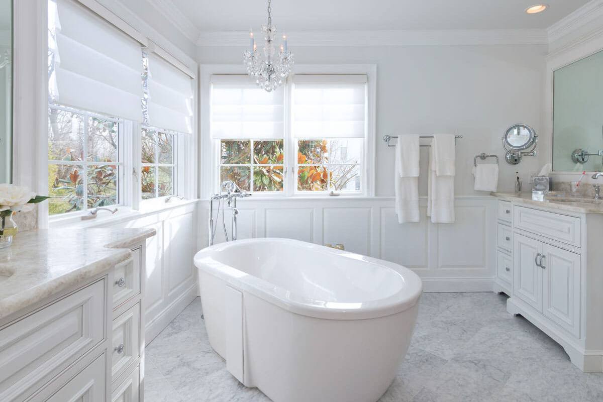 Freestanding tub below a chandelier in a Carrara marble bathroom