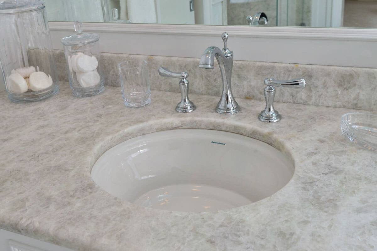 Undermount basin and silver-tone faucet in a leathered Antartide vanity top
