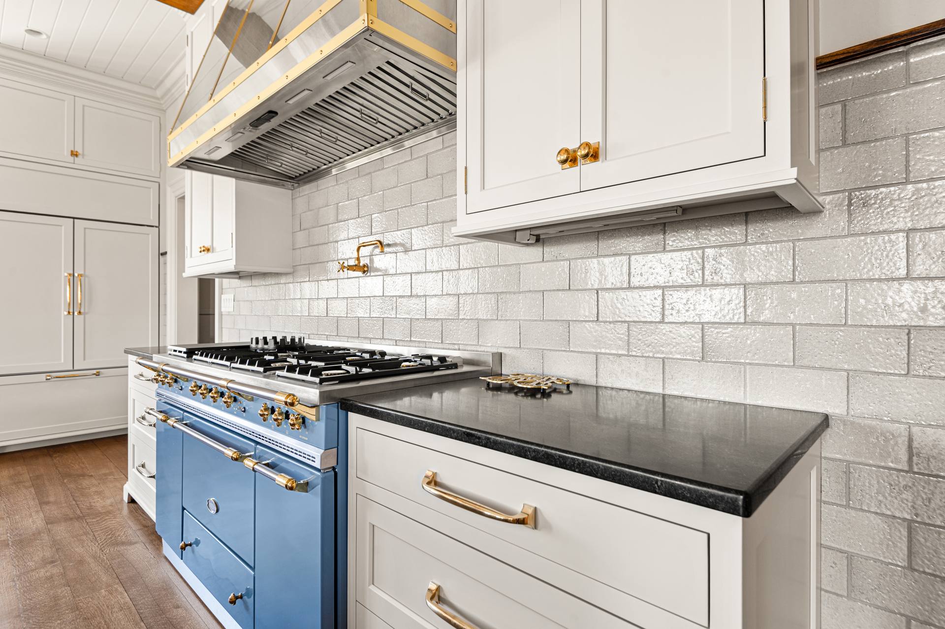 Blue range and gold-trimmed hood beside Black Absolute granite counters