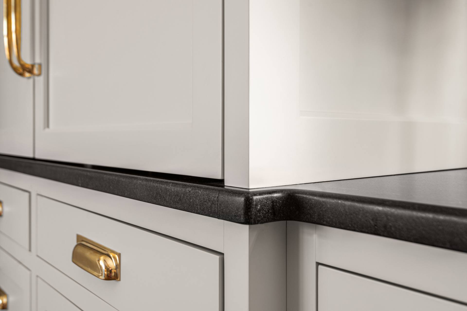 Black Absolute granite edge meeting a white apron sink front