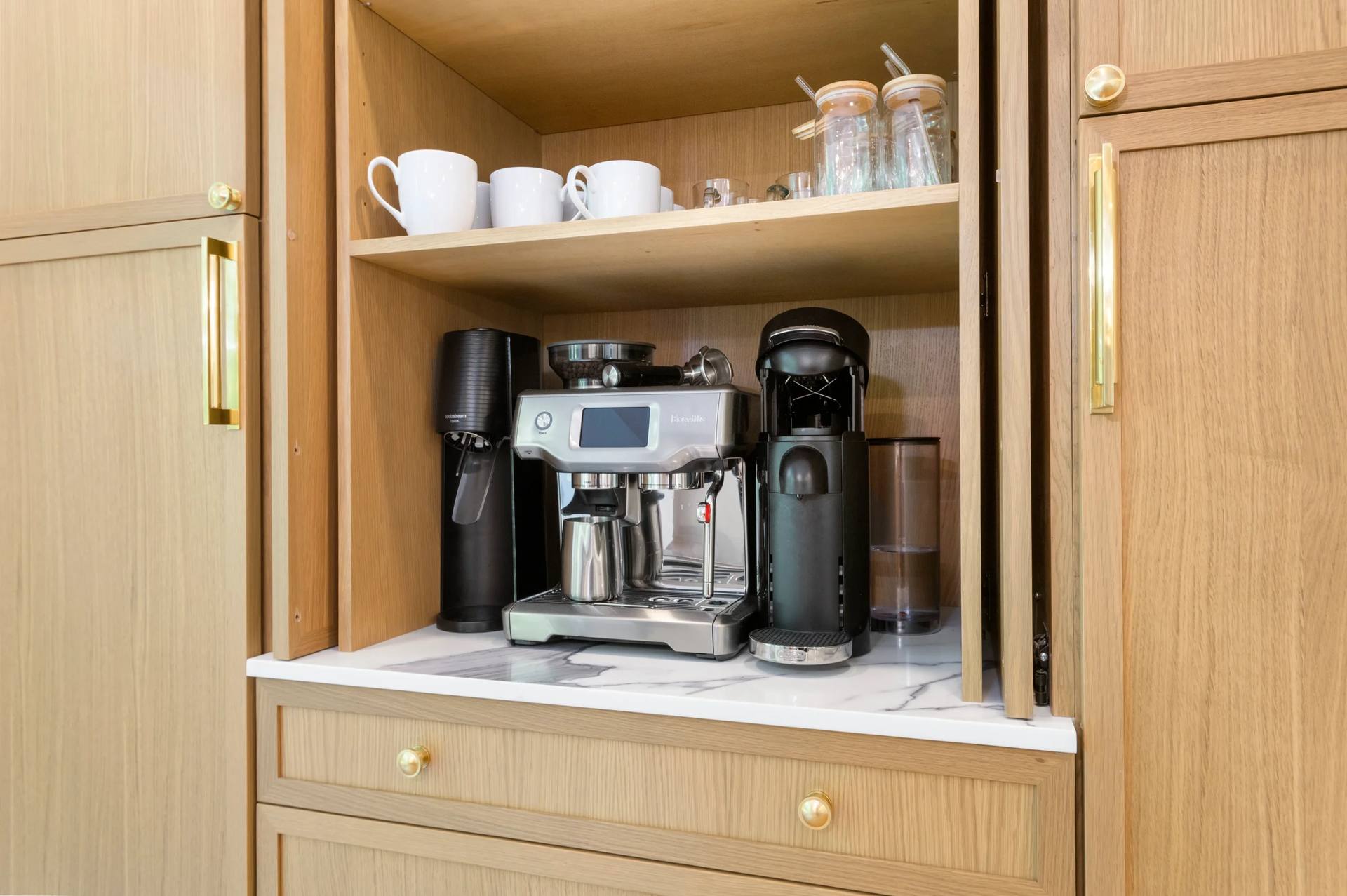 Coffee station with a Calacatta Corchia quartz counter inside a light wood cabinet
