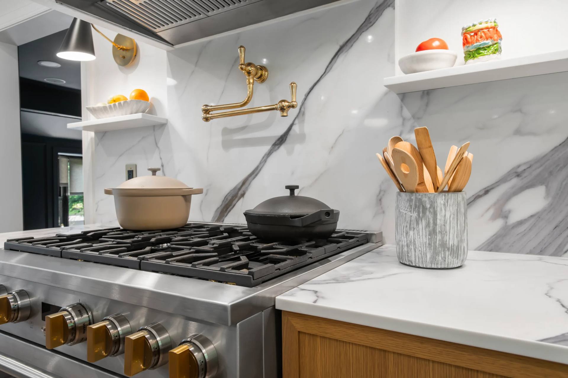Gold-tone pot filler on a Calacatta Corchia quartz backsplash above a gas range
