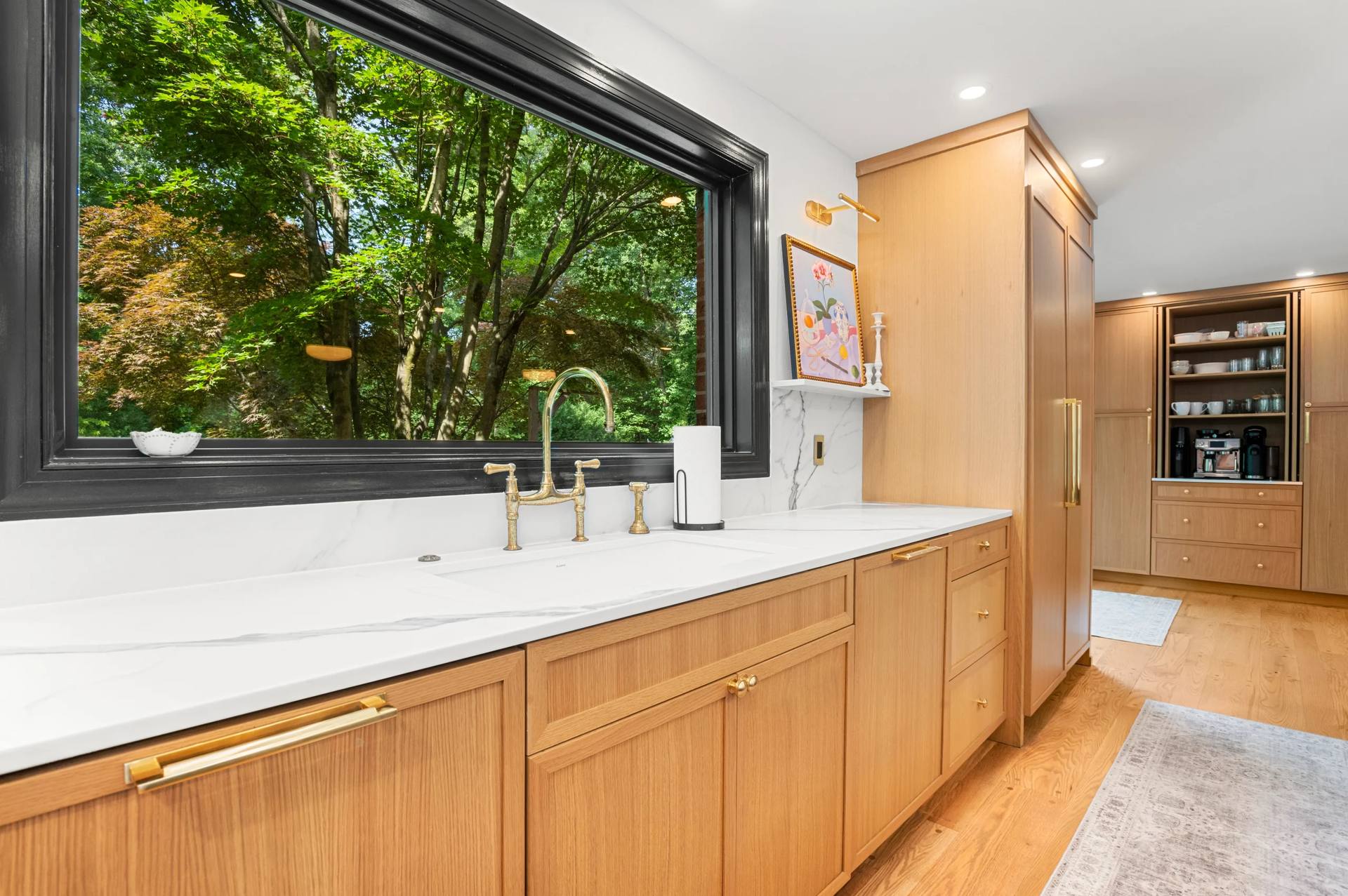 Calacatta Corchia quartz countertop under a picture window with a gold-tone faucet