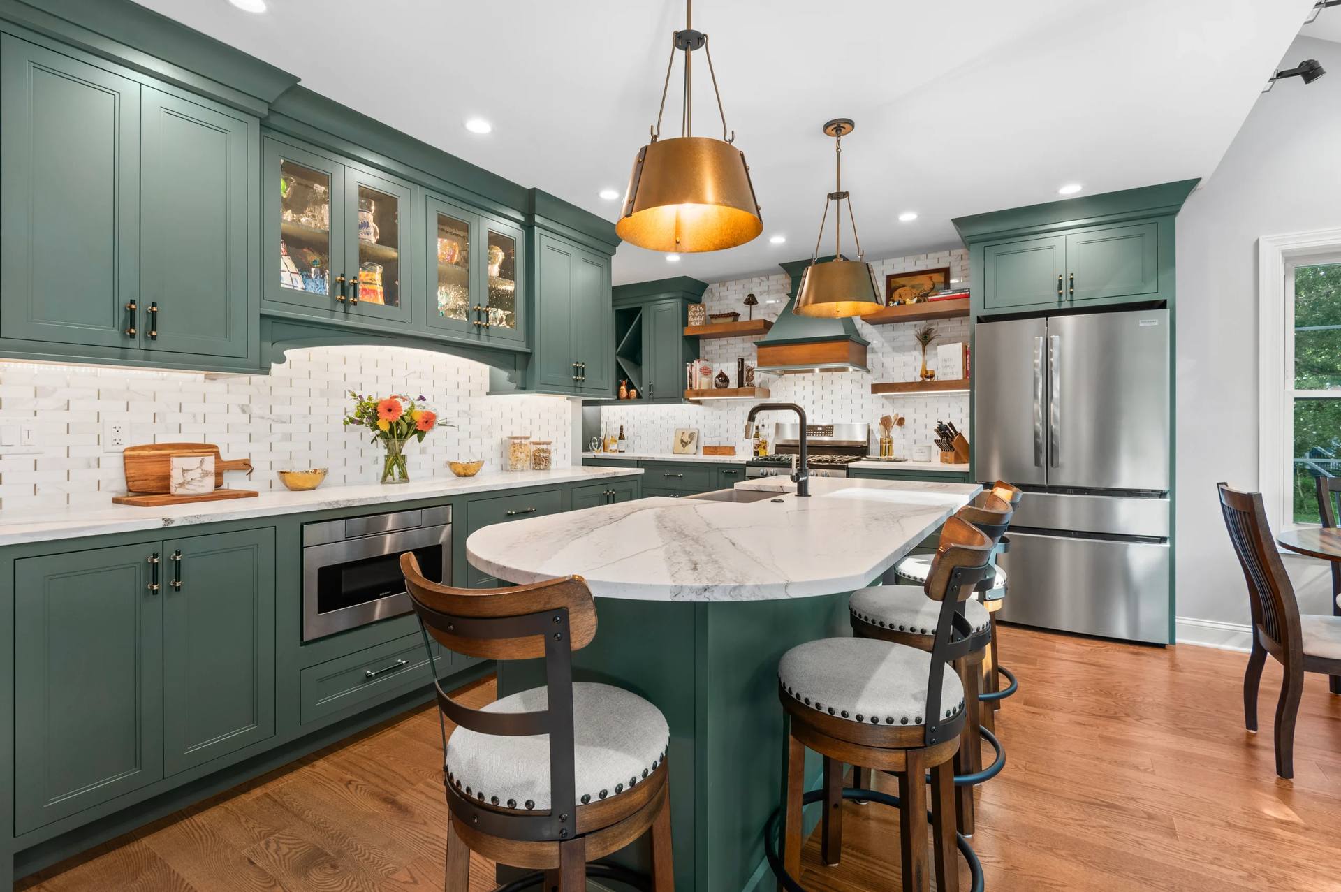 Curved Cambria Windsor Brass quartz counter with stools under gold-tone pendants