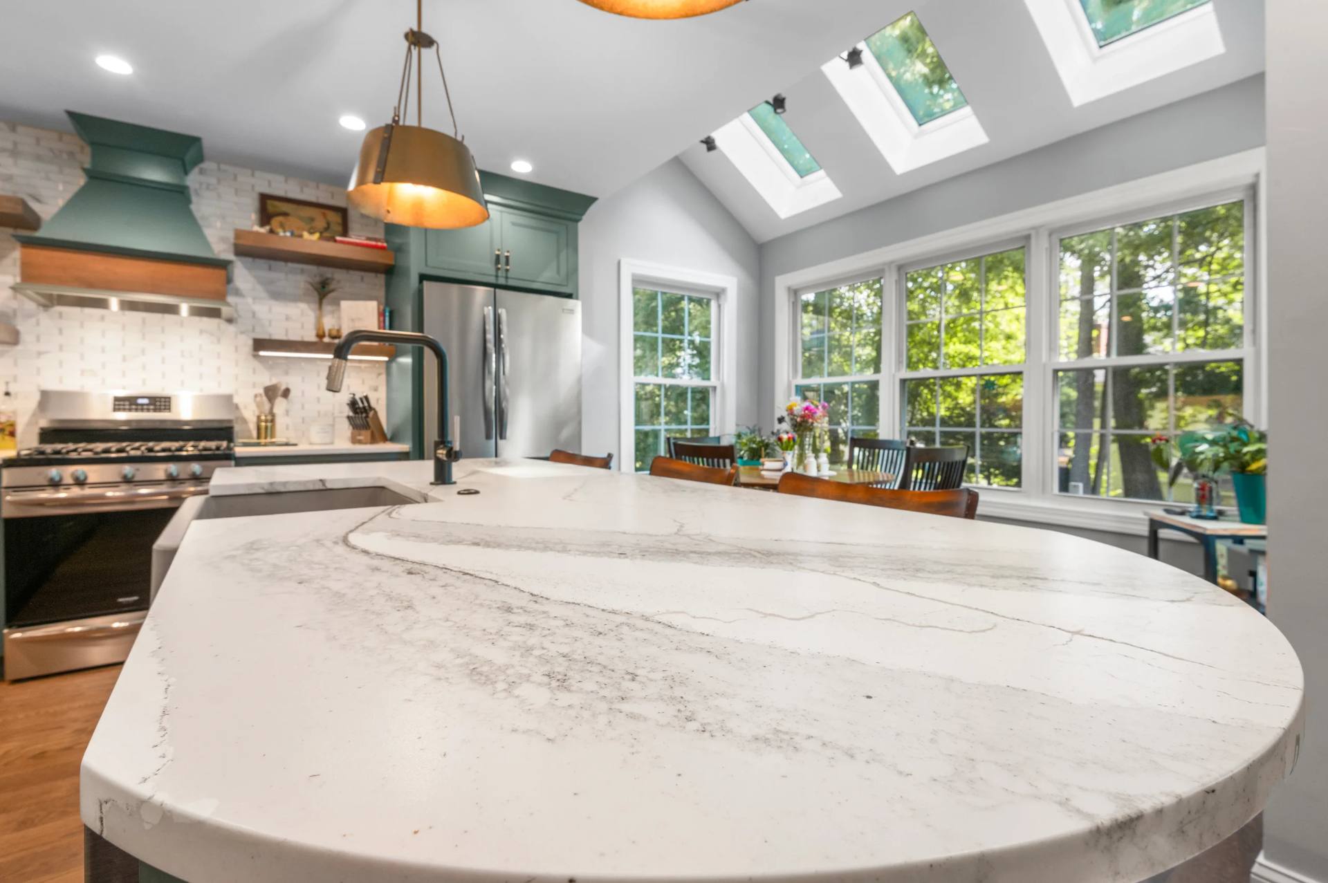 Broad curved Cambria Windsor Brass quartz island top with gray veining