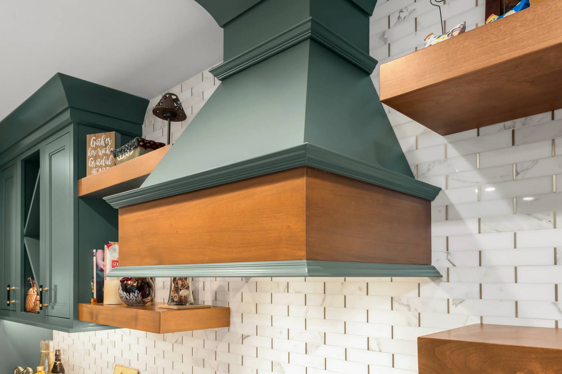 Wood range hood and floating shelves above a tile backsplash