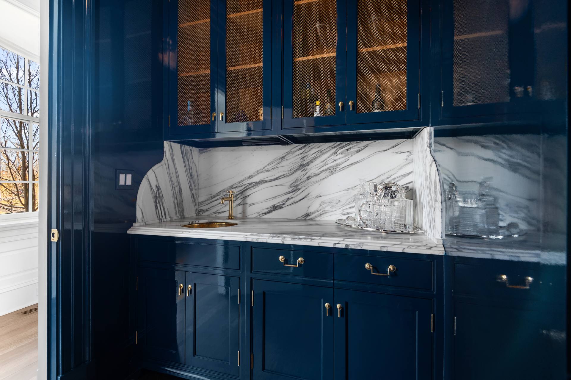 Navy bar cabinetry with a Calacatta Corchia marble counter and backsplash