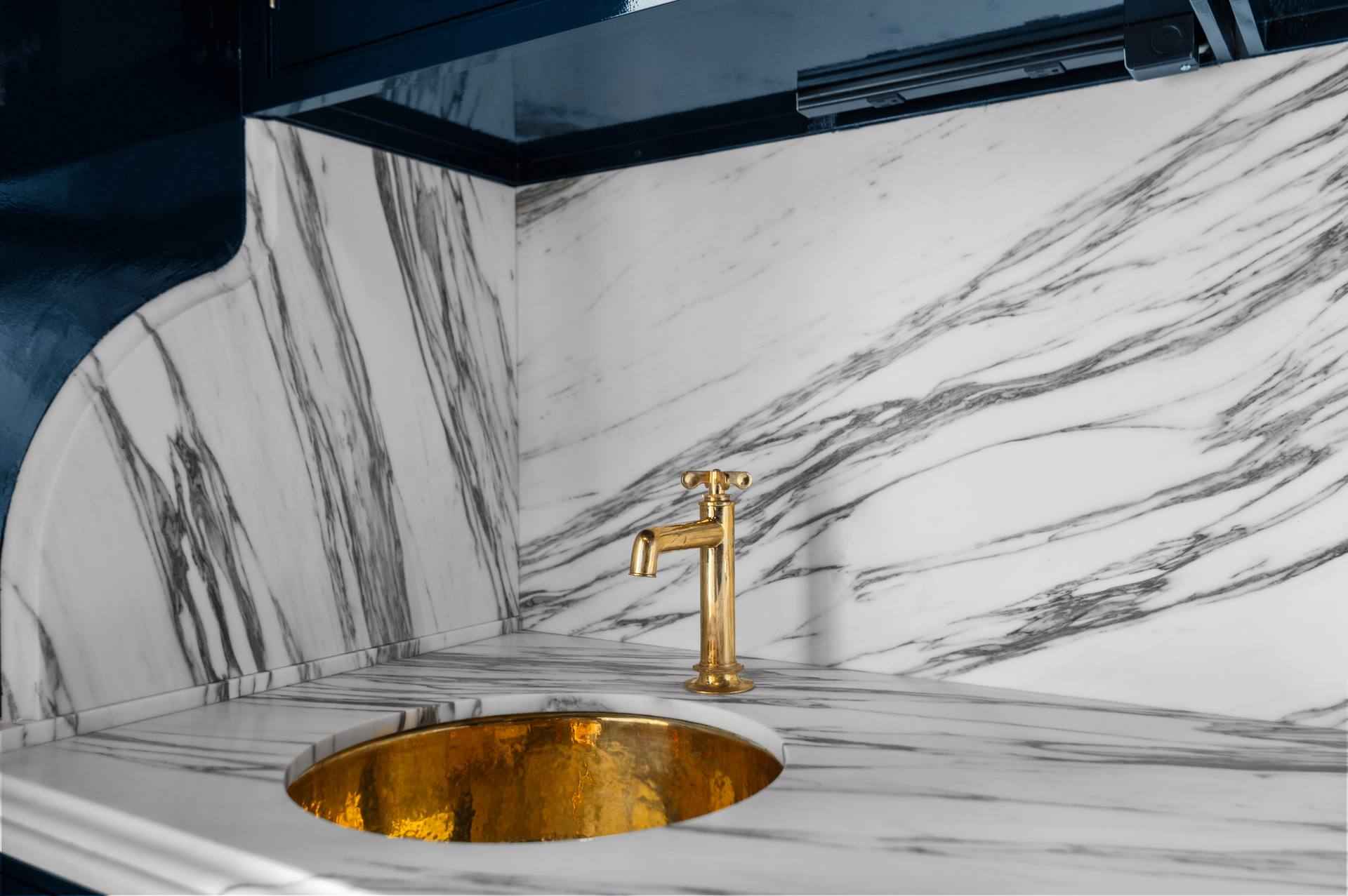 Hammered gold-tone bar sink set into a Calacatta Corchia marble counter