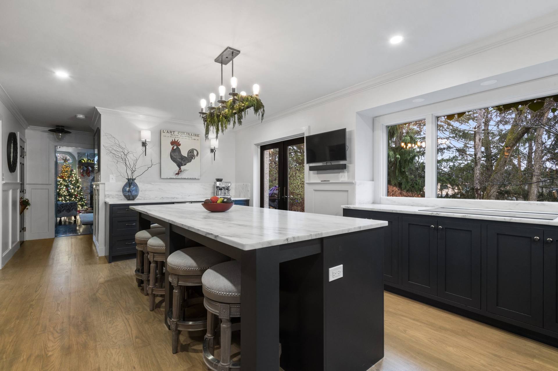 End of a honed Danby marble island with stools and a chandelier above