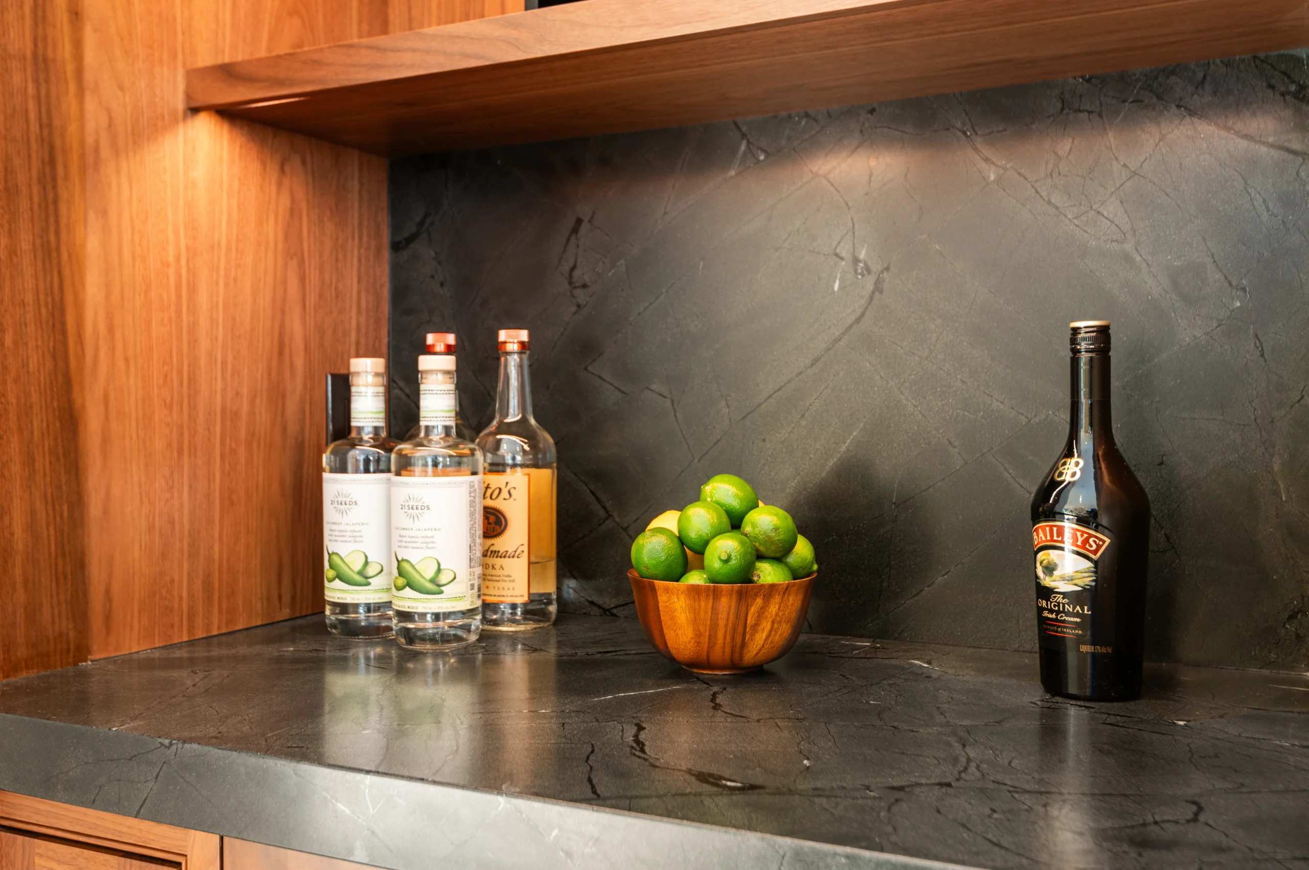 Black stone countertop and backsplash installed in a wood home bar