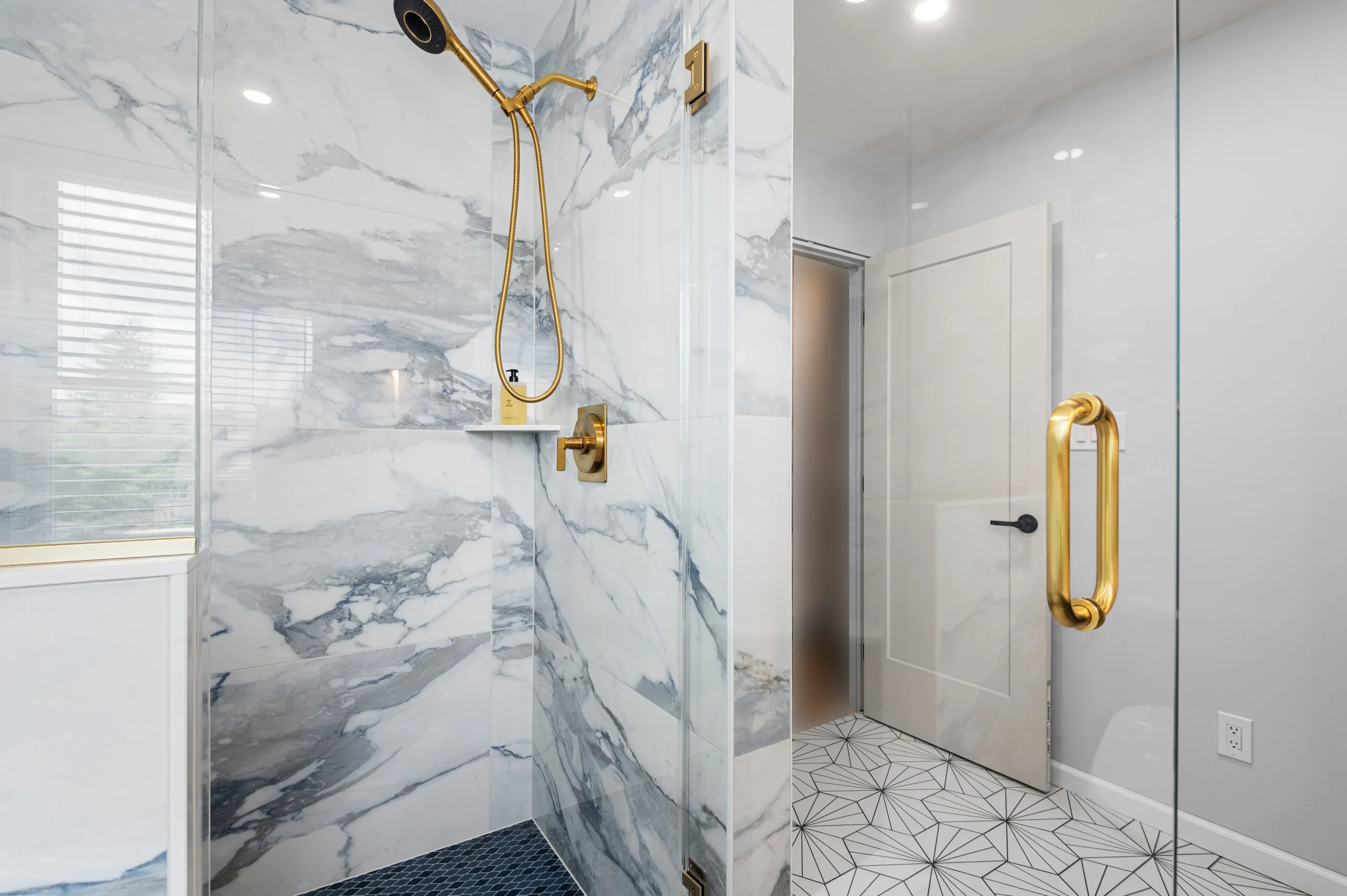 Porcelain shower walls with blue-gray veining and brass fixtures