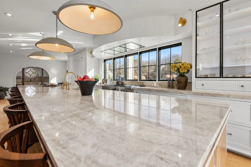 Taj Mahal quartzite island with double laminated edges, white cabinets and brass fixtures