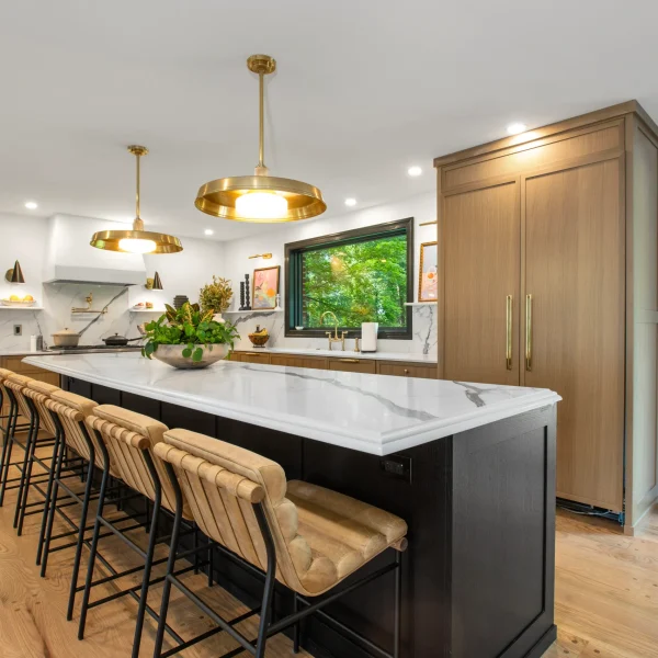 White quartz kitchen island with black cabinets and brass lighting