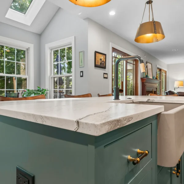 White countertop with a farmhouse sink on green kitchen cabinets