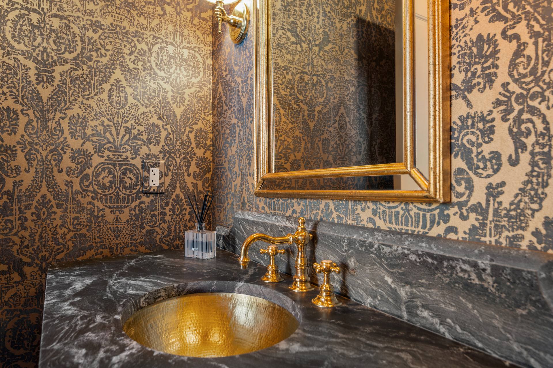 Gold-tone faucet above a hammered gold-tone basin in leathered granite