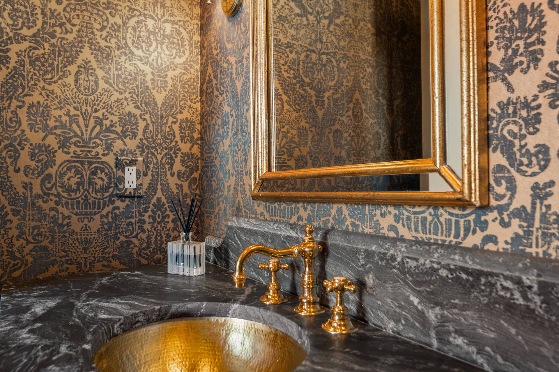 Leathered granite vanity top with a hammered brass basin and gold-tone faucet