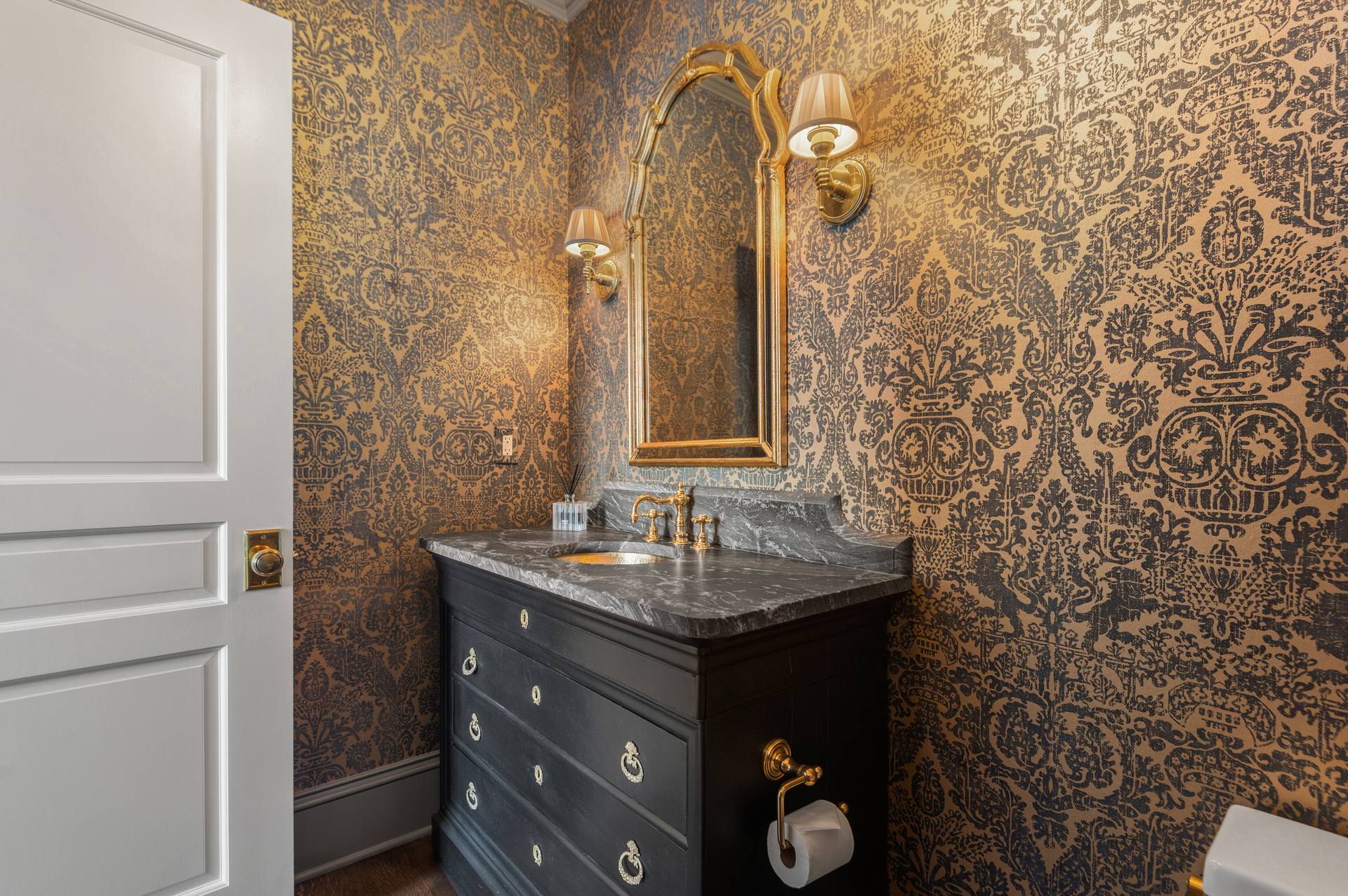 Bathroom vanity with a leathered granite top against patterned wallpaper