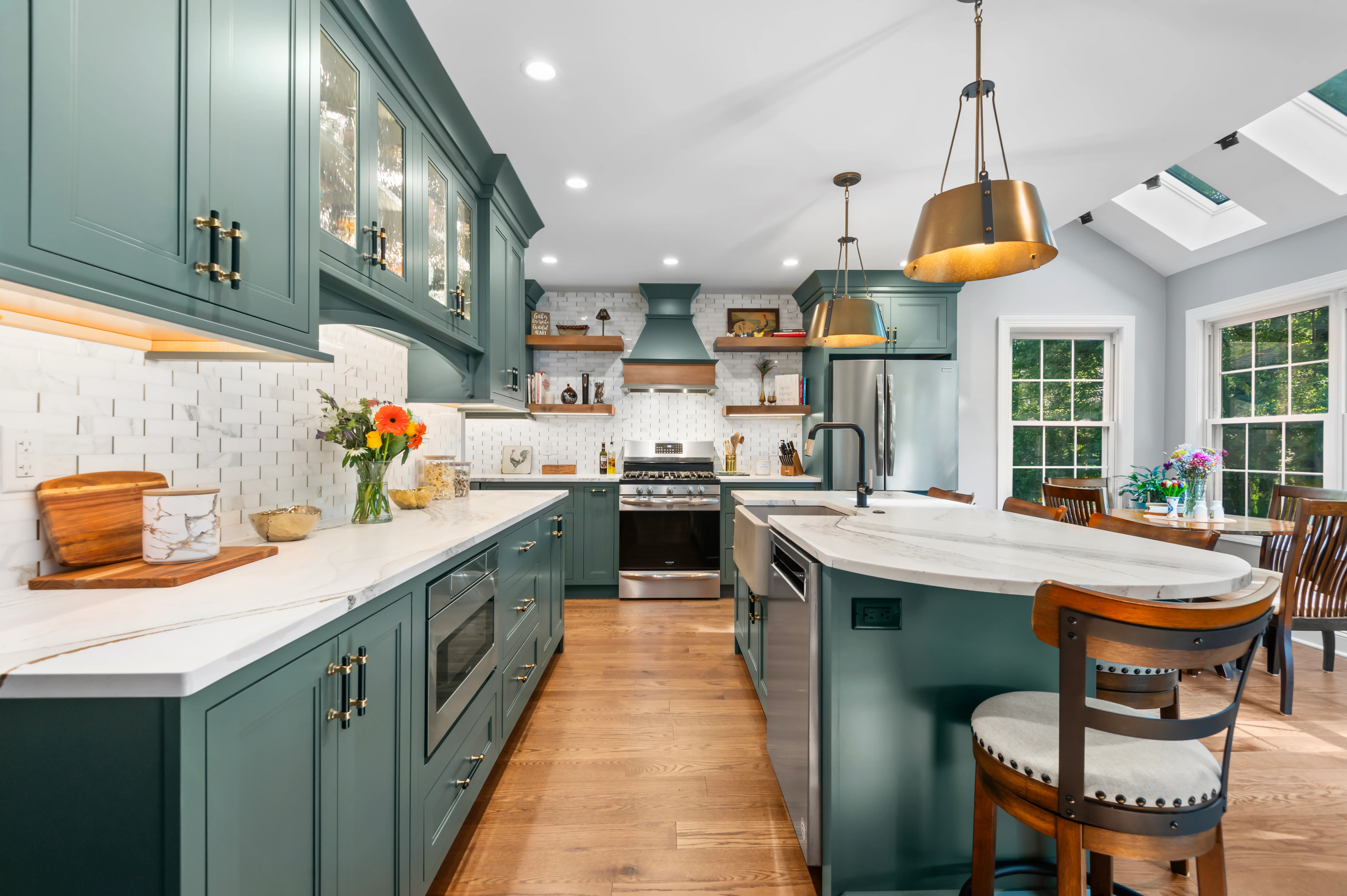 Cambria Windsor Brass quartz countertops in a green kitchen with gold-tone pendant lights