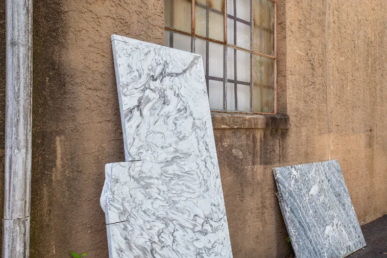 Three patterned stone remnants leaning against the Cosmos warehouse