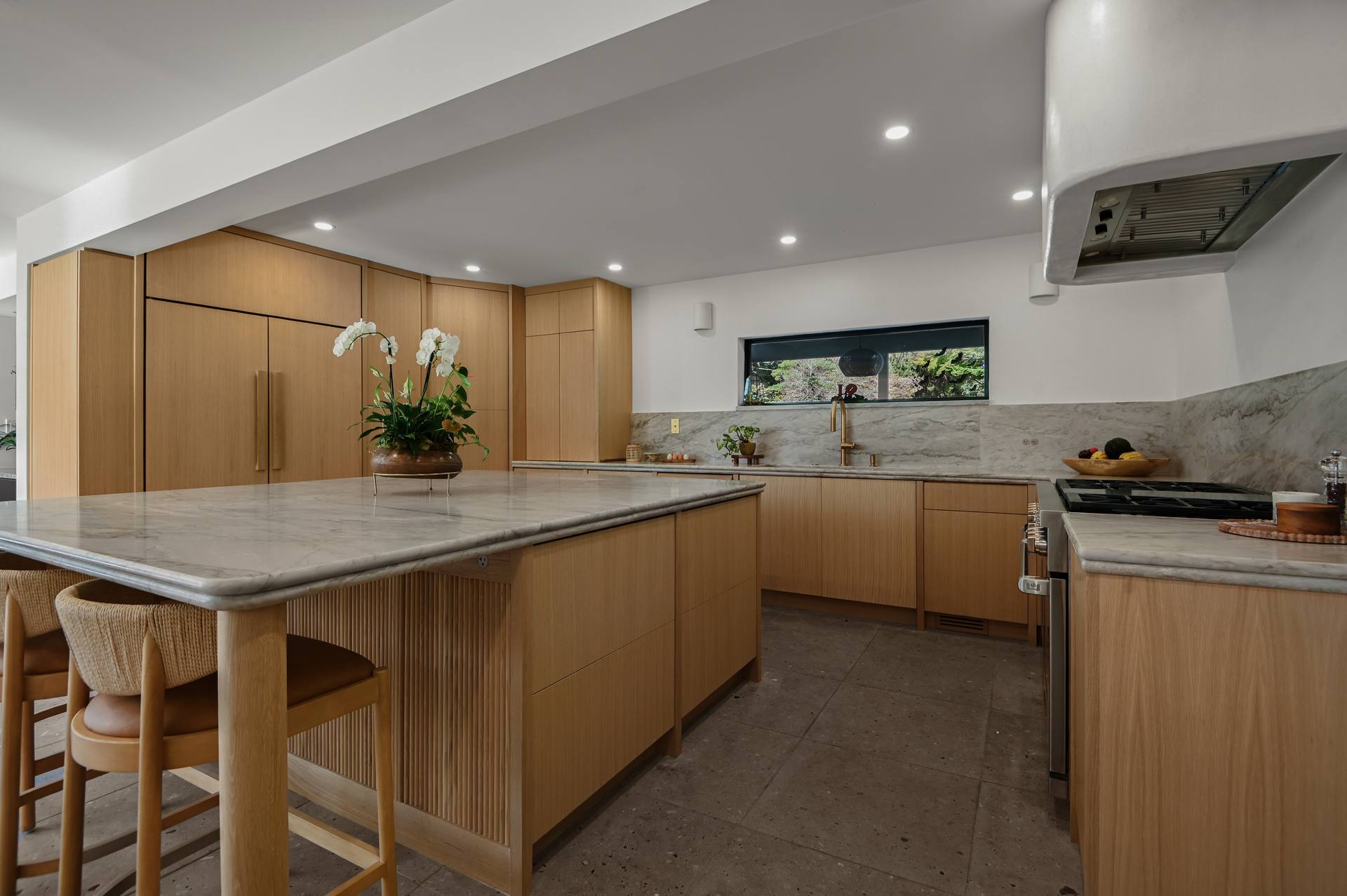 Sea Pearl quartzite island and perimeter countertops below a curved plaster range hood