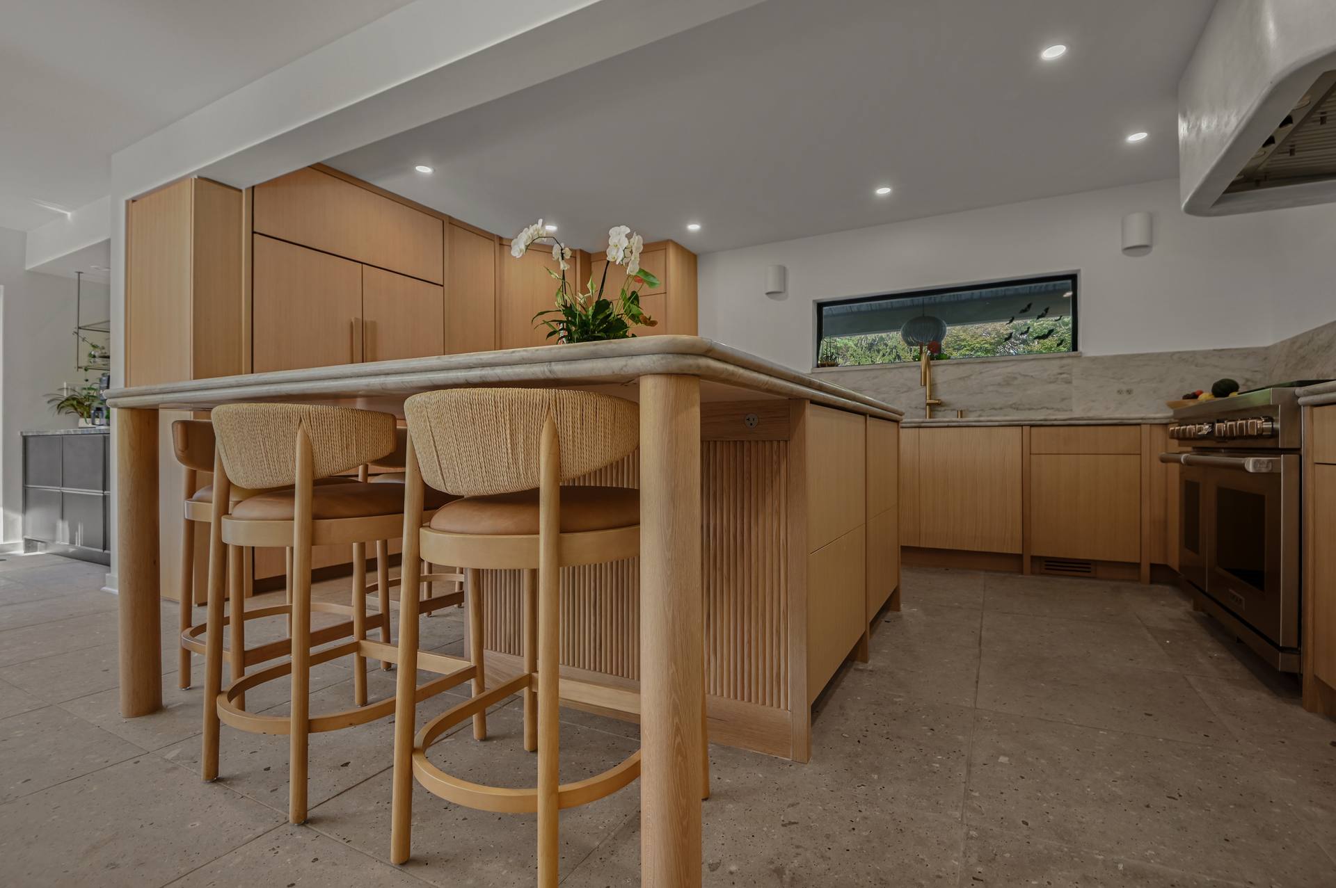 Sea Pearl quartzite island with counter stools and a fluted oak base
