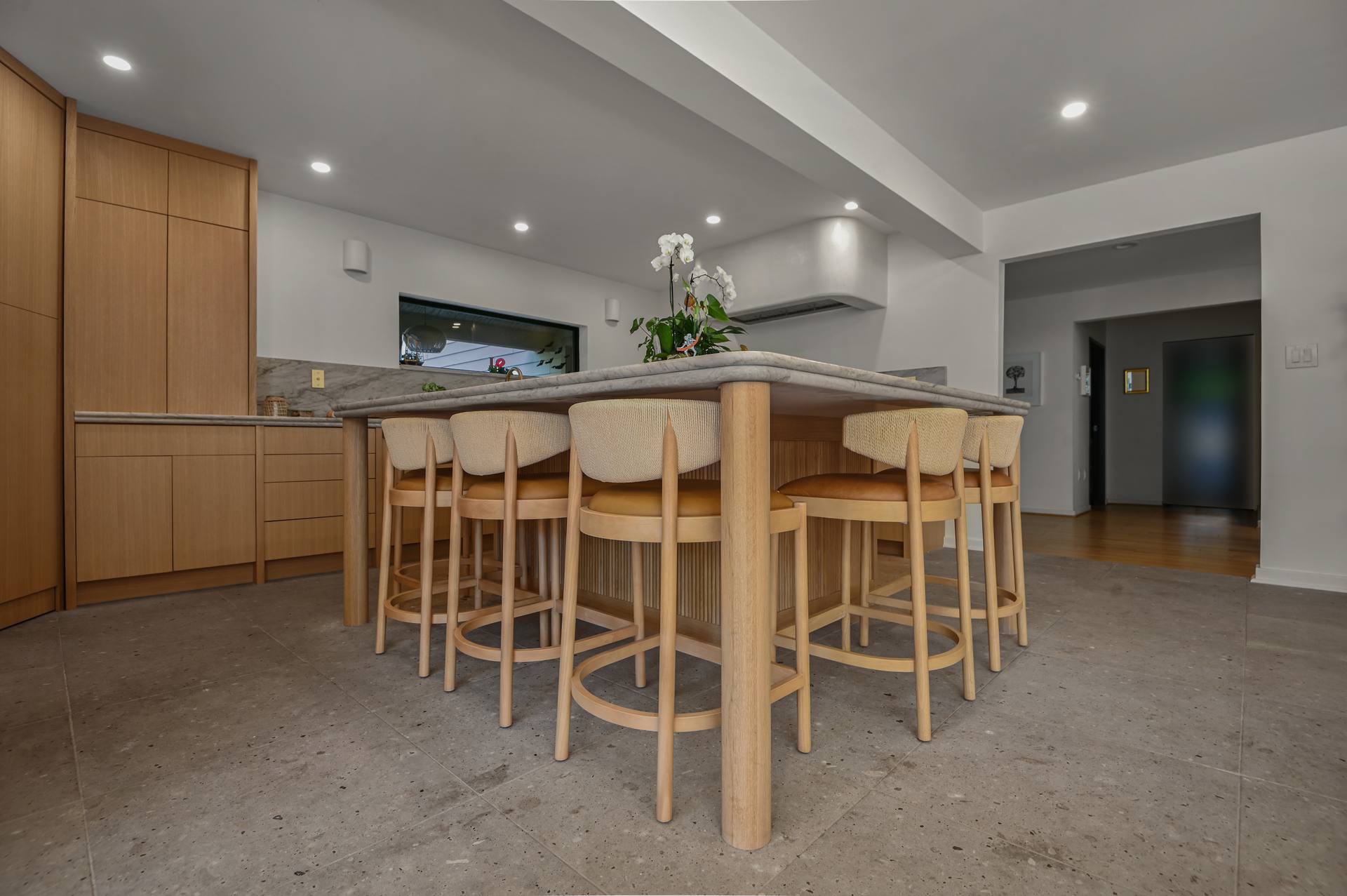 Five counter stools at a Sea Pearl quartzite island on round oak legs