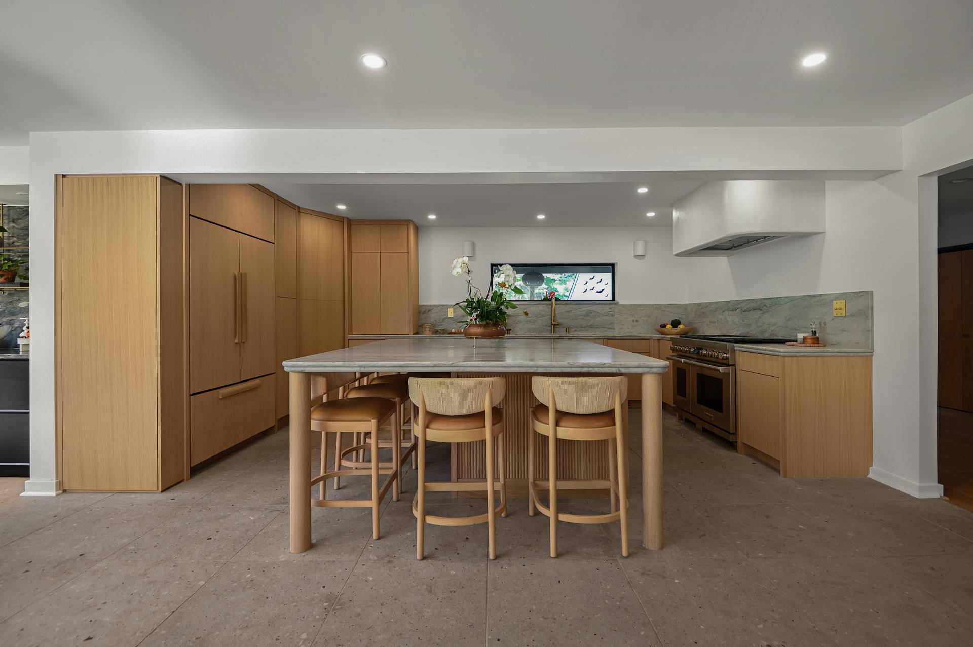 Kitchen with a Sea Pearl quartzite island, oak cabinetry and counter stools
