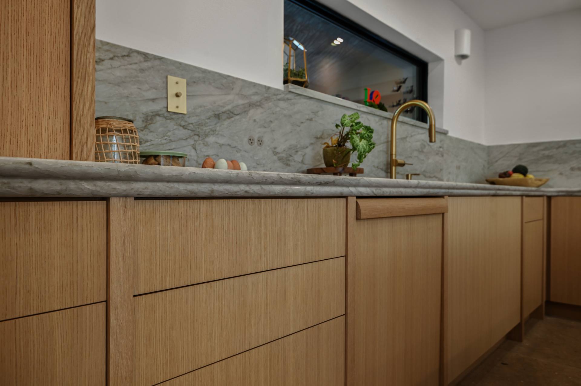Sea Pearl quartzite counter and backsplash running above oak drawers