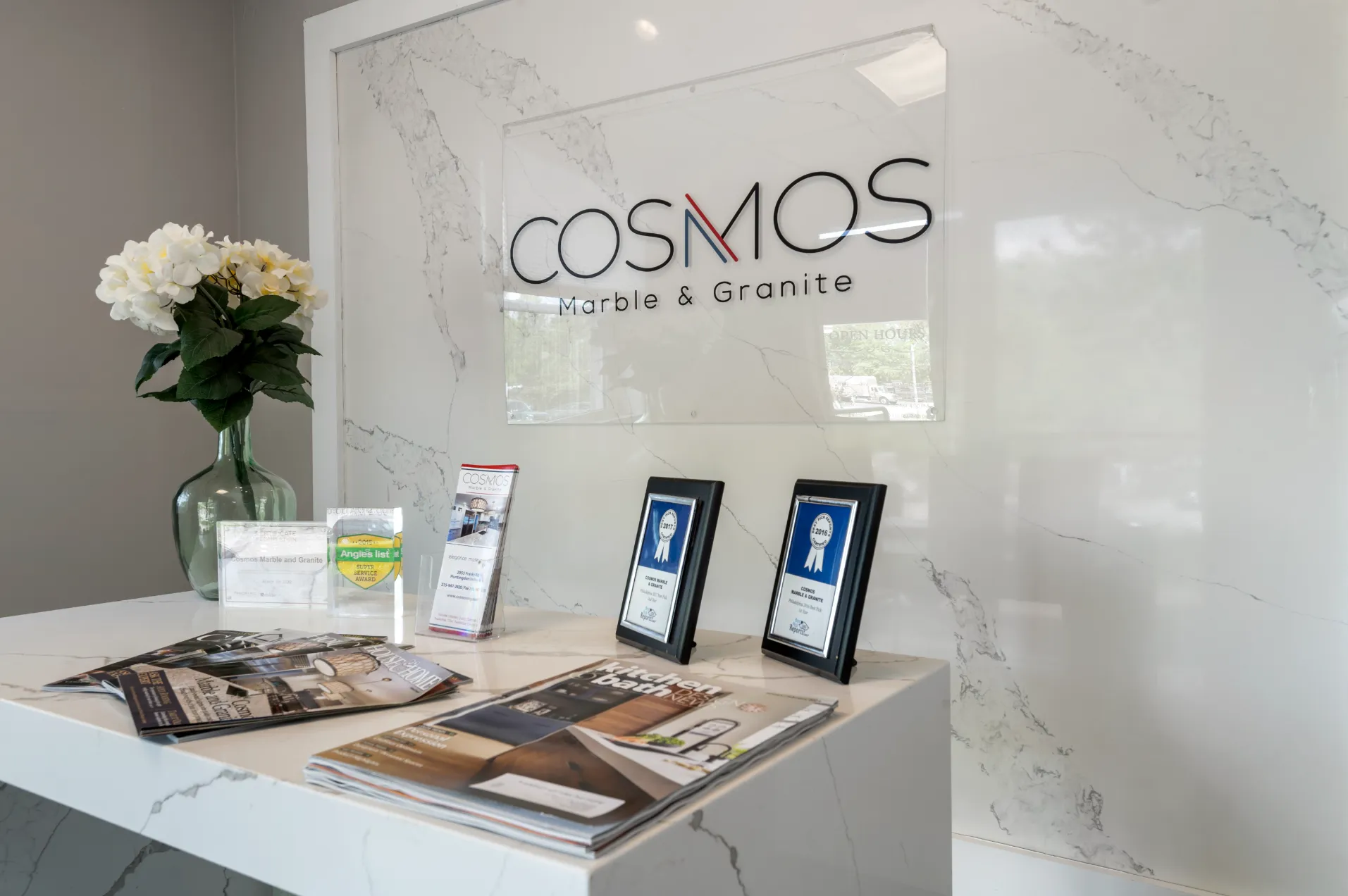 Cosmos Marble and Granite showroom display with the company logo, flowers, and awards