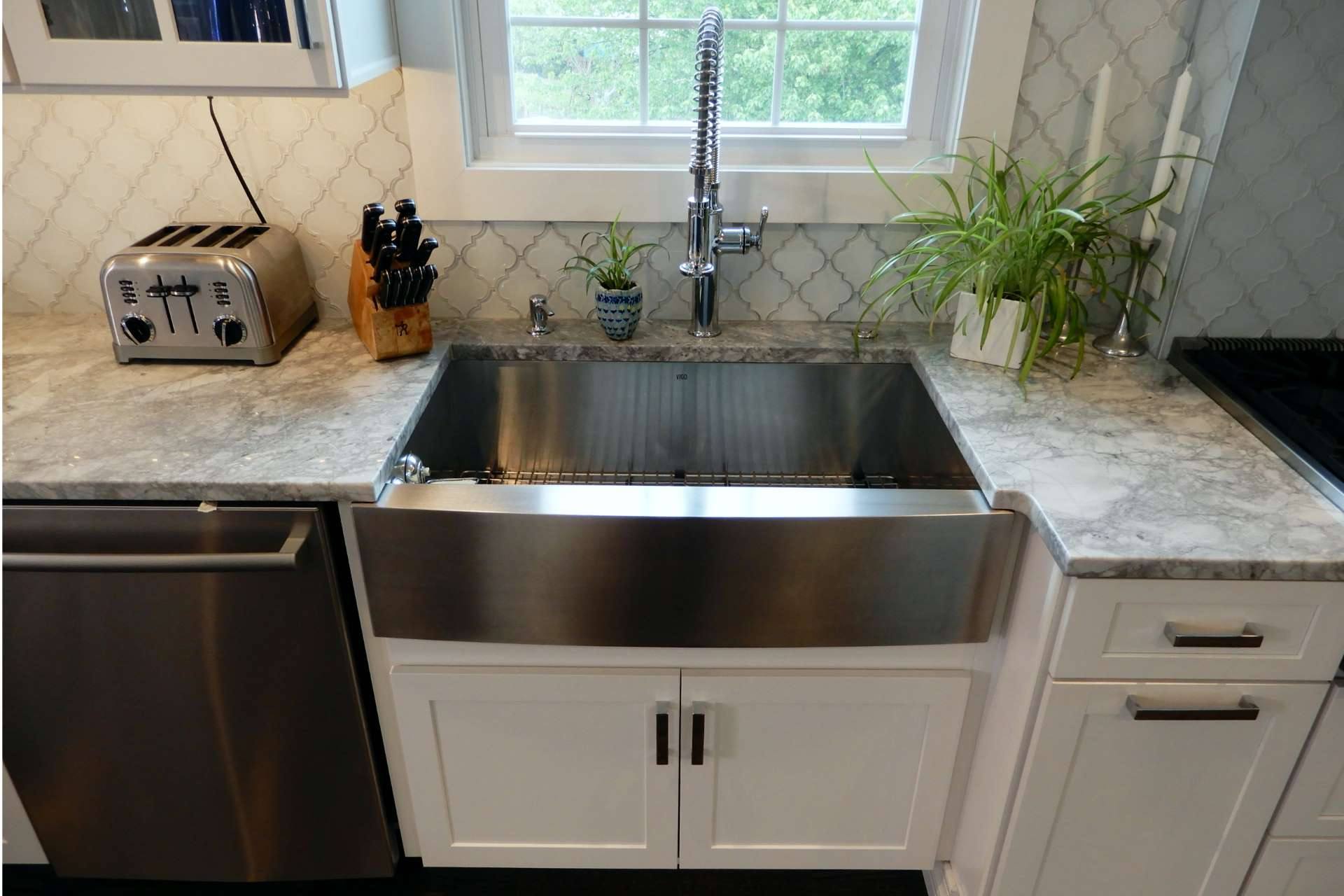 Metal apron sink set into a Super White quartzite counter below a window