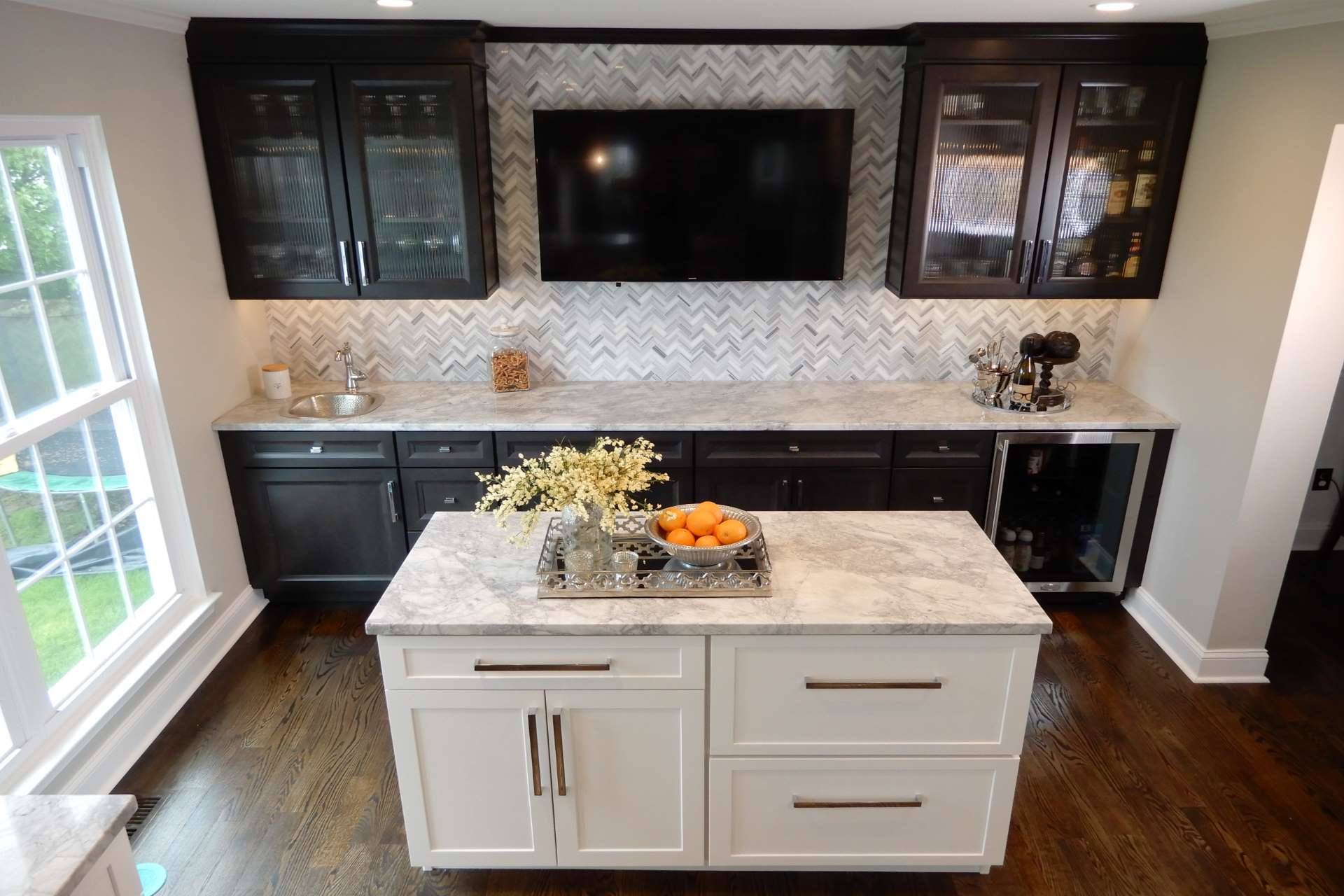 Super White quartzite island below dark cabinets and herringbone tile