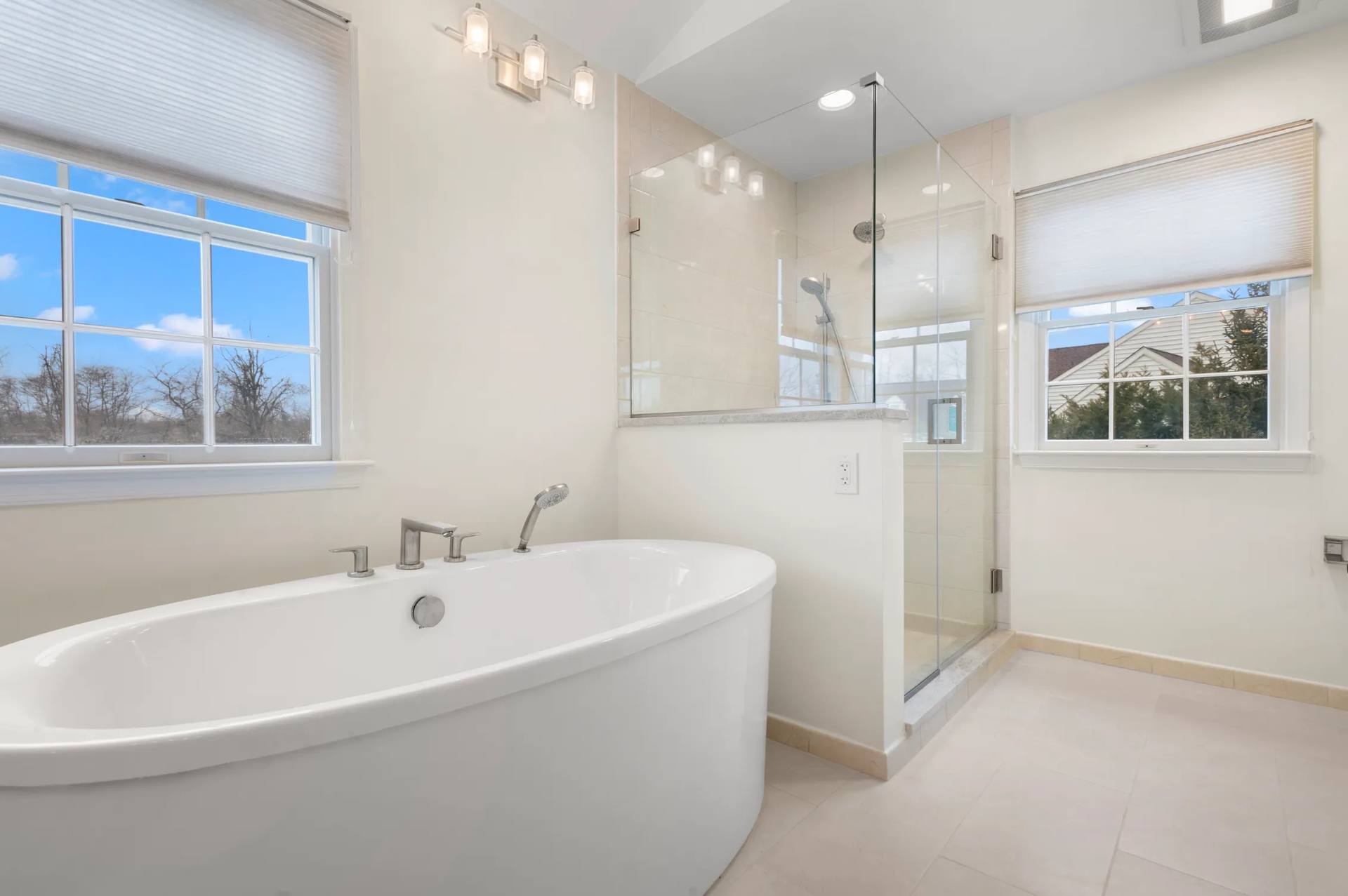 Freestanding tub beside a glass shower in a bathroom with quartzite vanities