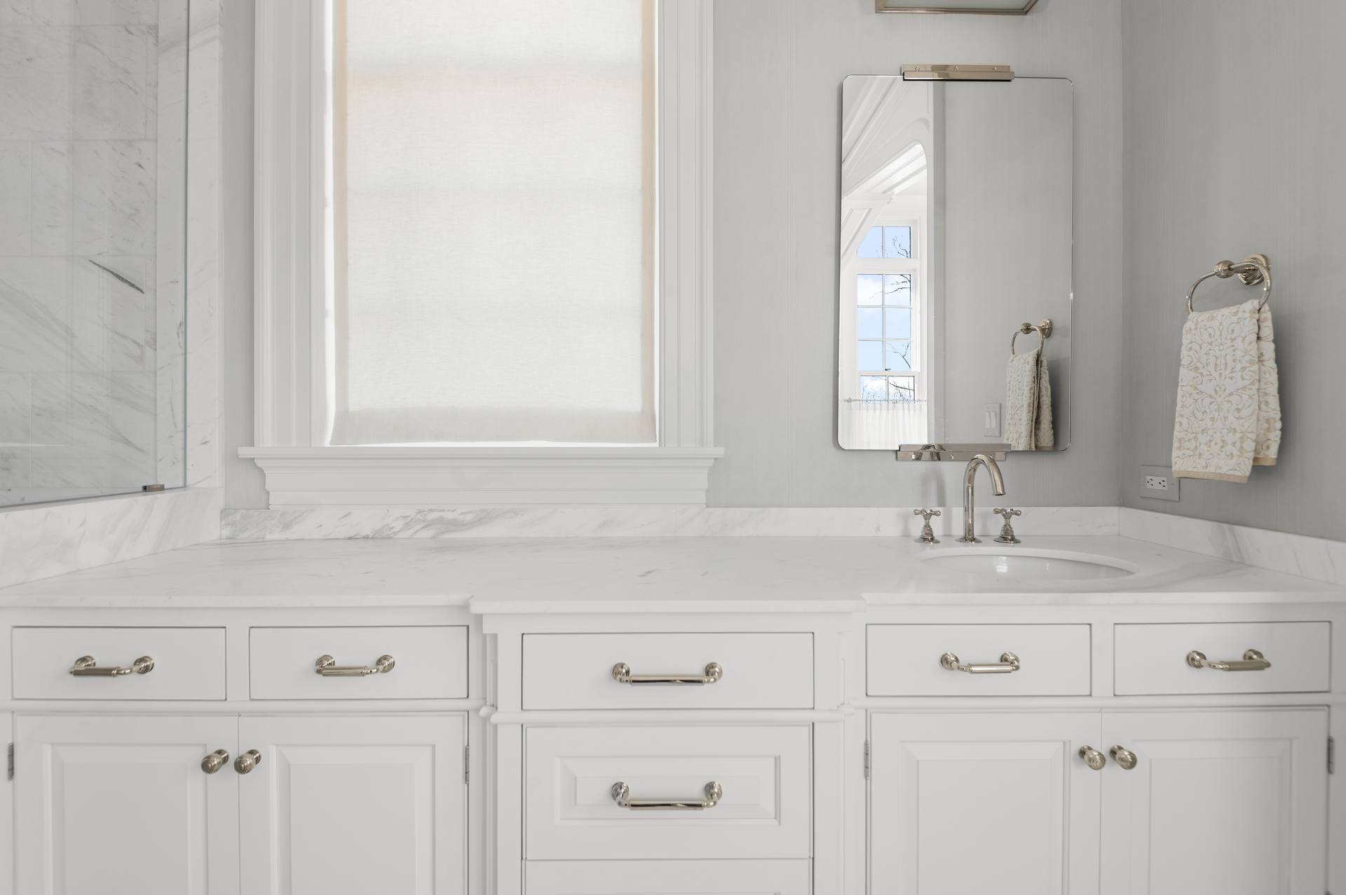 Thassos marble vanity top below a mirror and window