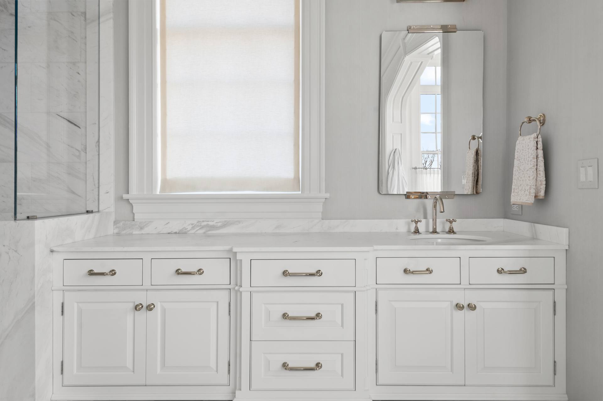 Thassos marble vanity beside a marble wall panel