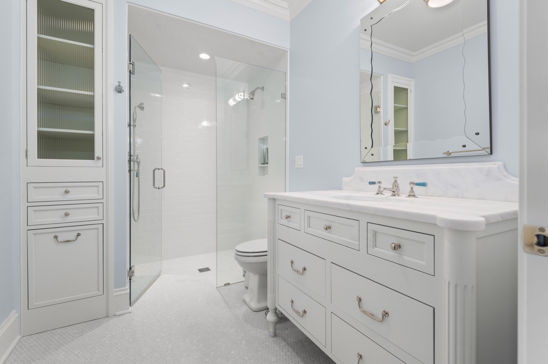 Pale blue bathroom with a White Carrara marble vanity top and a tiled shower