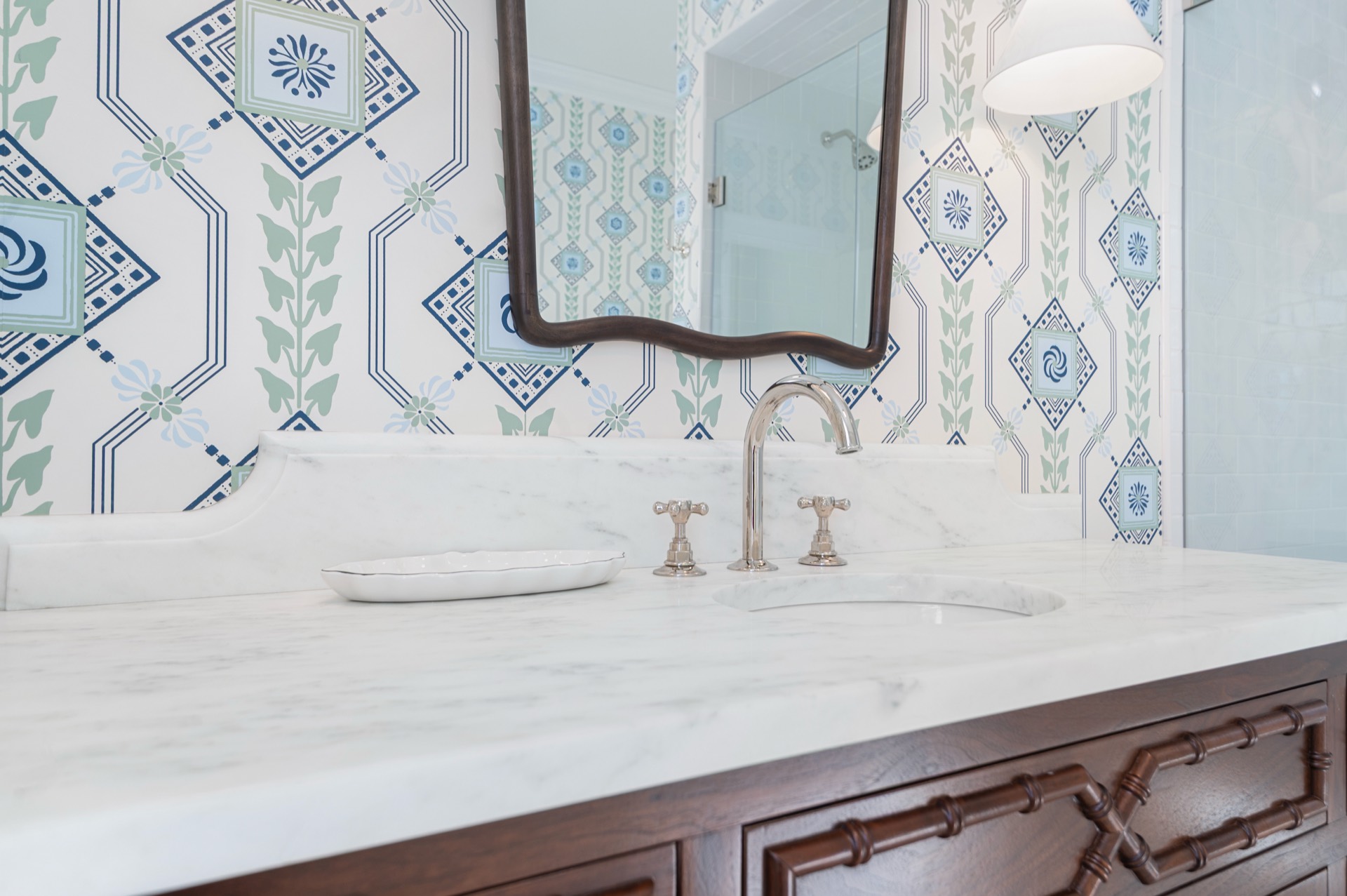 Shaped White Carrara marble backsplash rising behind a silver-tone faucet