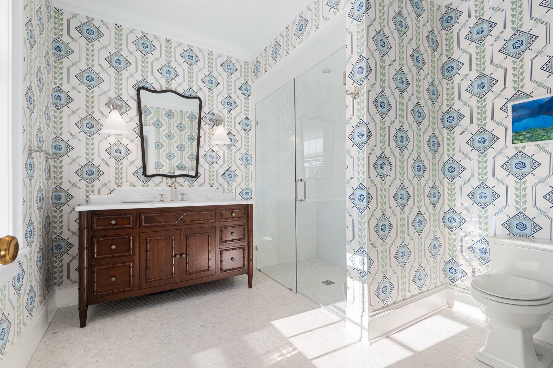 Wallpapered bathroom with a White Carrara marble vanity top and a glass shower