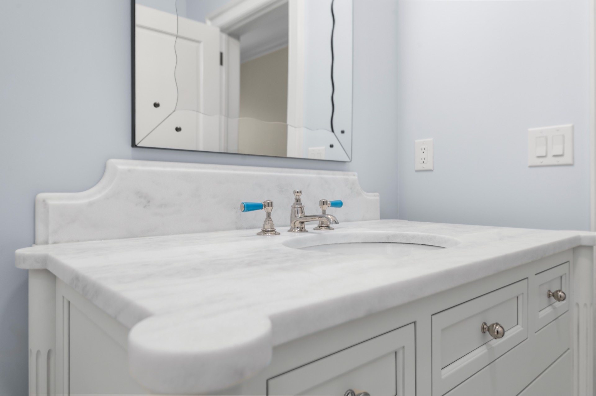 White Carrara marble vanity top with a shaped backsplash on a white painted cabinet