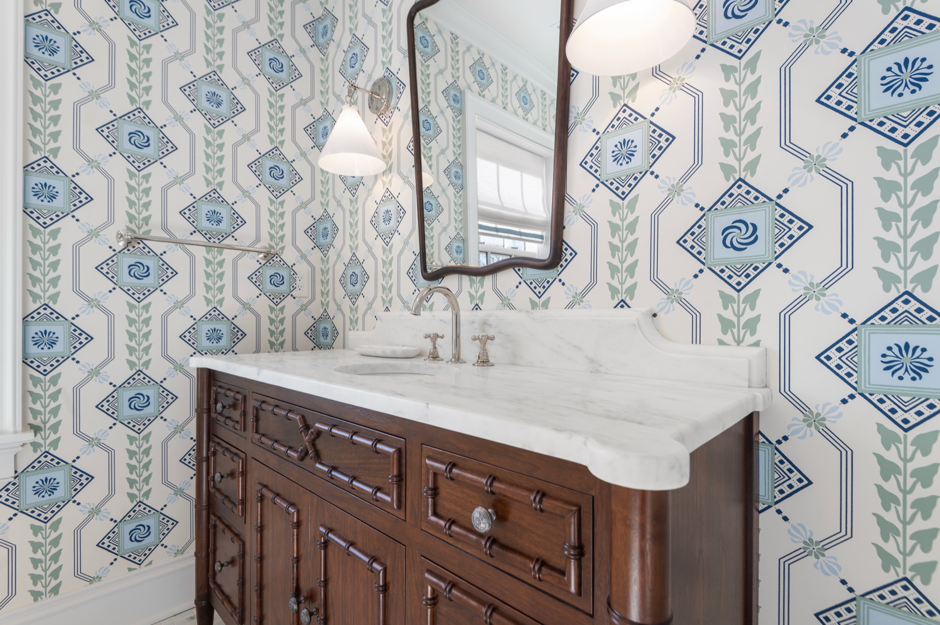 Angled view of a White Carrara marble vanity top beneath a wavy wood mirror
