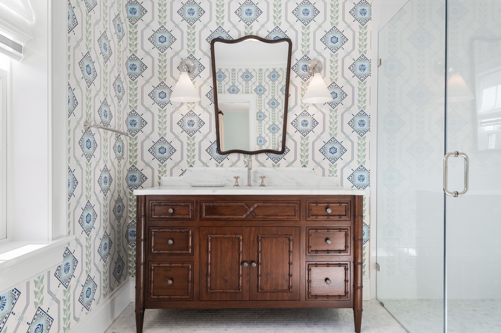 White Carrara marble vanity top on a dark wood cabinet in a wallpapered bathroom