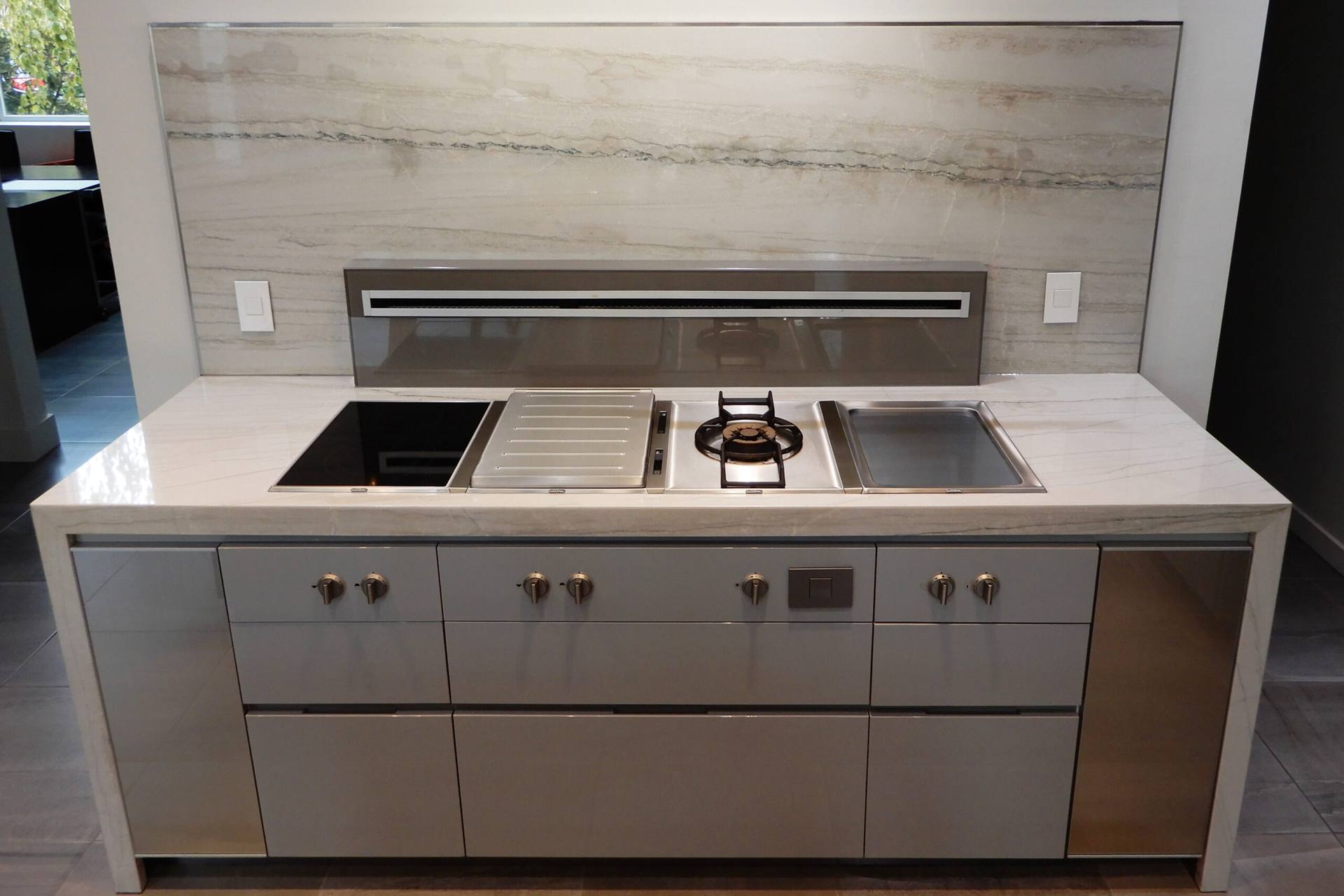 White Macaubas quartzite counter above handleless cabinets at the cooktop