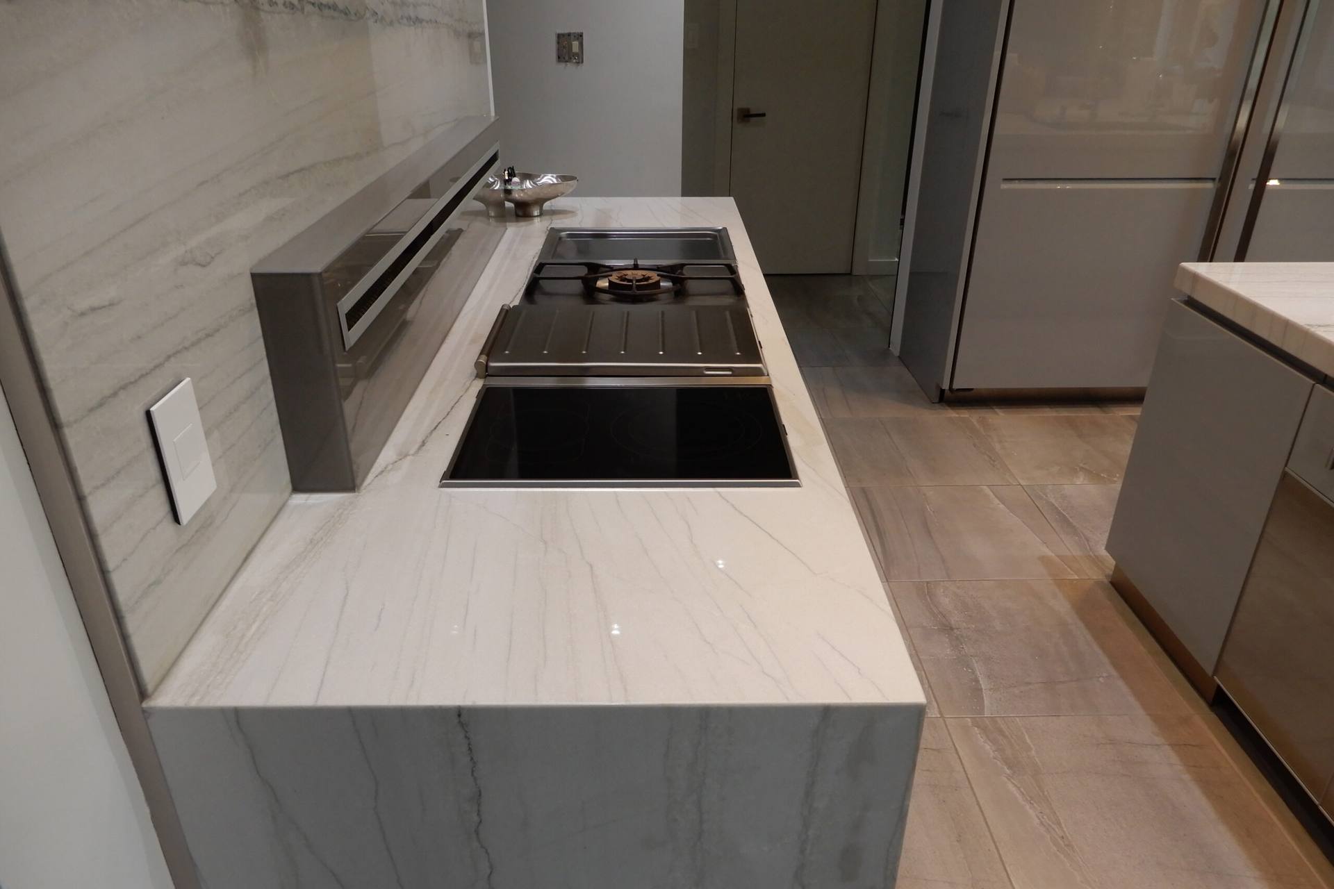 Cooktop below a full-height White Macaubas quartzite backsplash panel
