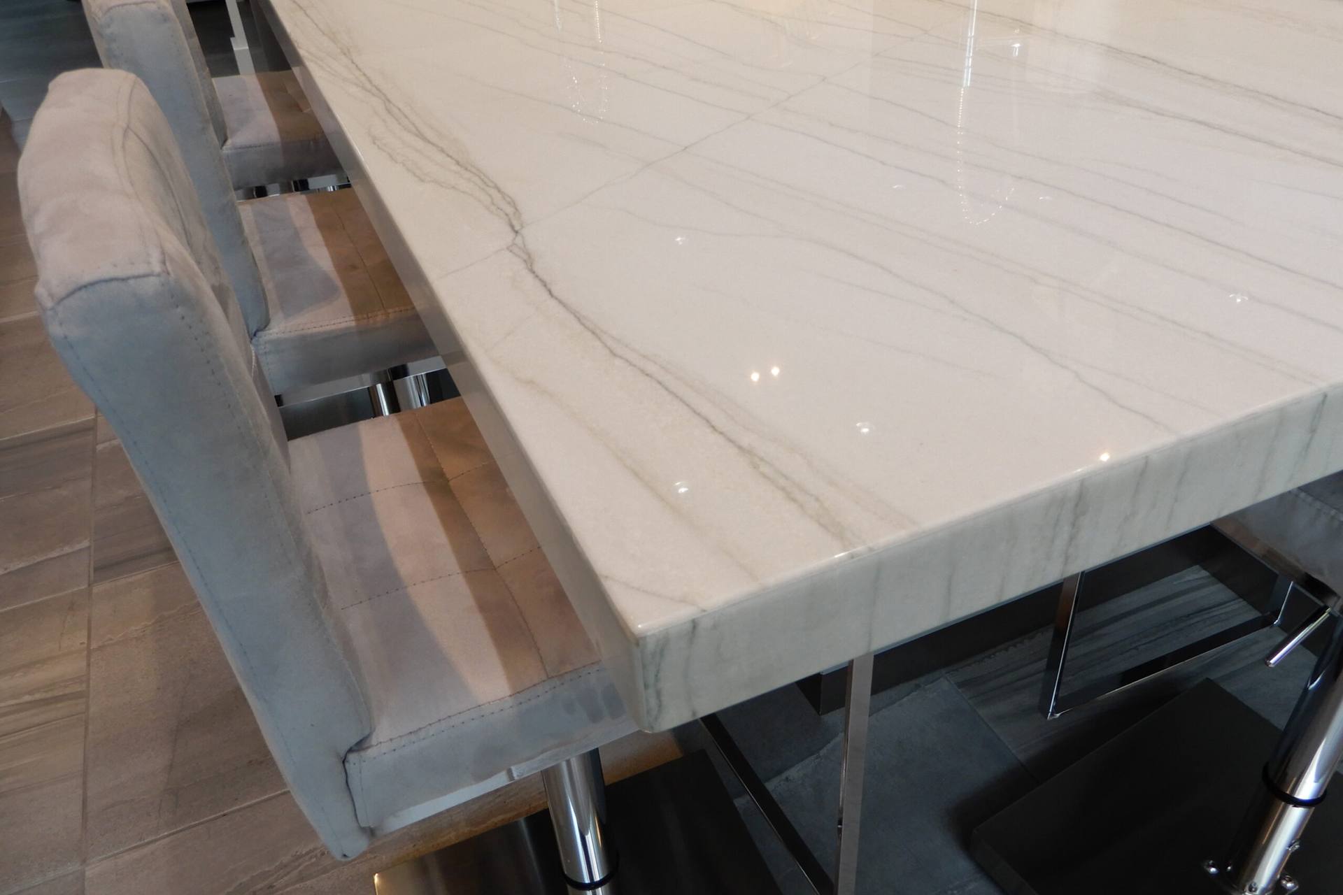 Edge of a White Macaubas quartzite island above upholstered stools