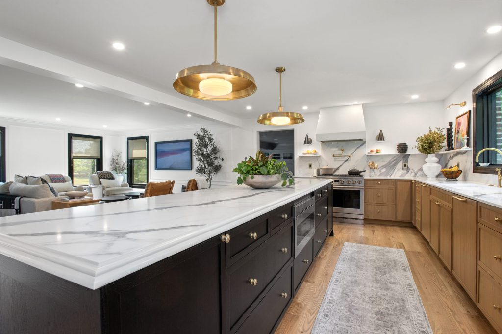 White kitchen with a dark island and light stone countertops