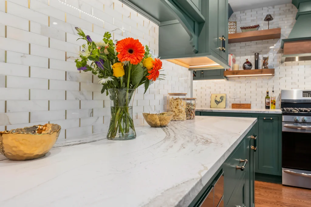 White kitchen countertop beside green cabinets and a subway tile backsplash