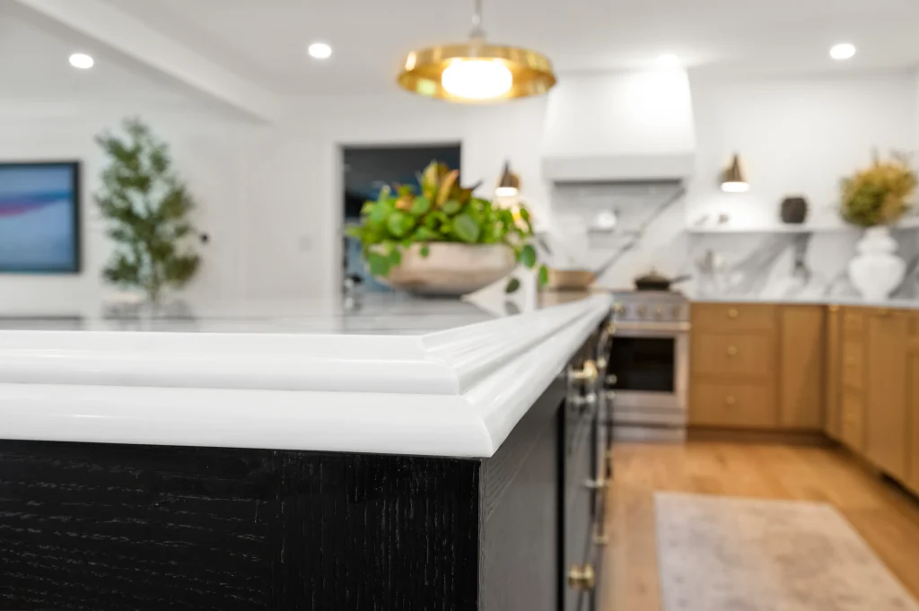 White kitchen with a dark island and light stone countertops